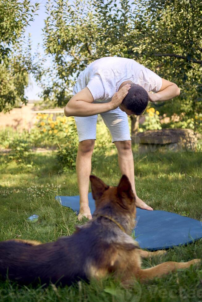 man does somatic exercises with his dog in the garden in the morning photo