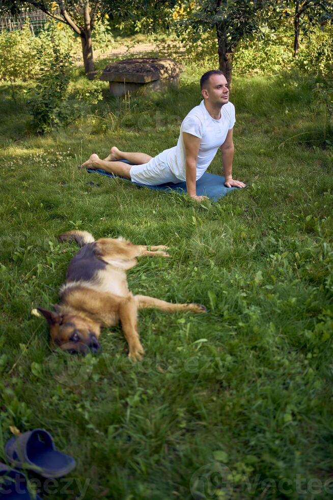man does somatic exercises with his dog in the garden in the morning photo