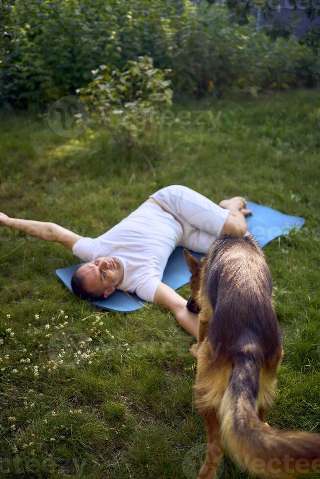 man does somatic exercises with his dog in the garden in the morning photo