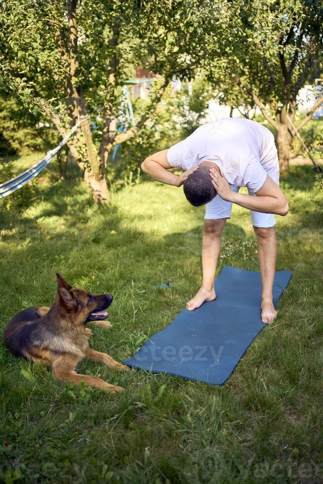man does somatic exercises with his dog in the garden in the morning photo