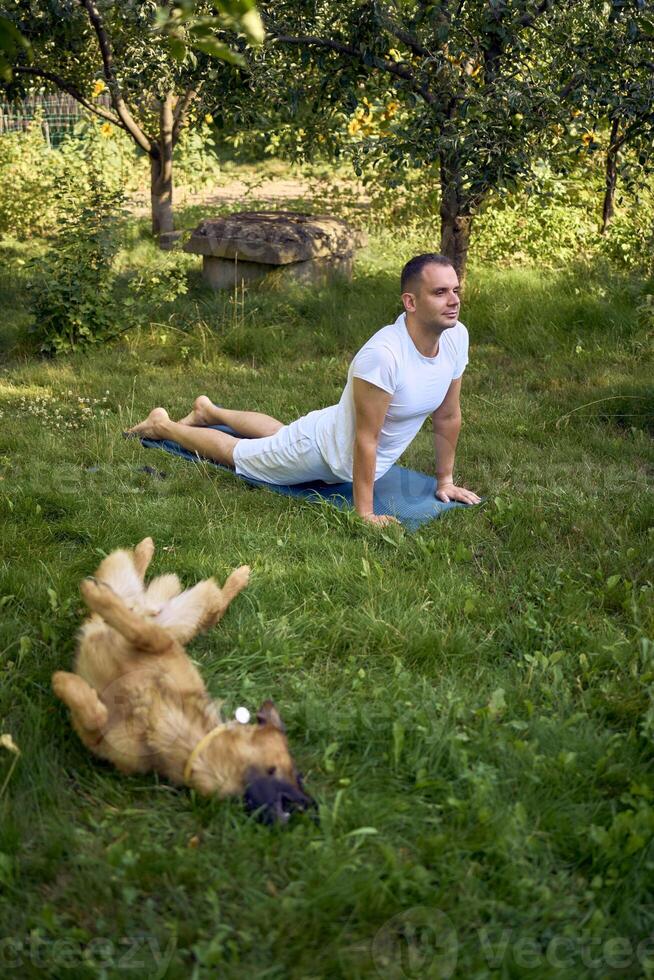 man does somatic exercises with his dog in the garden in the morning photo