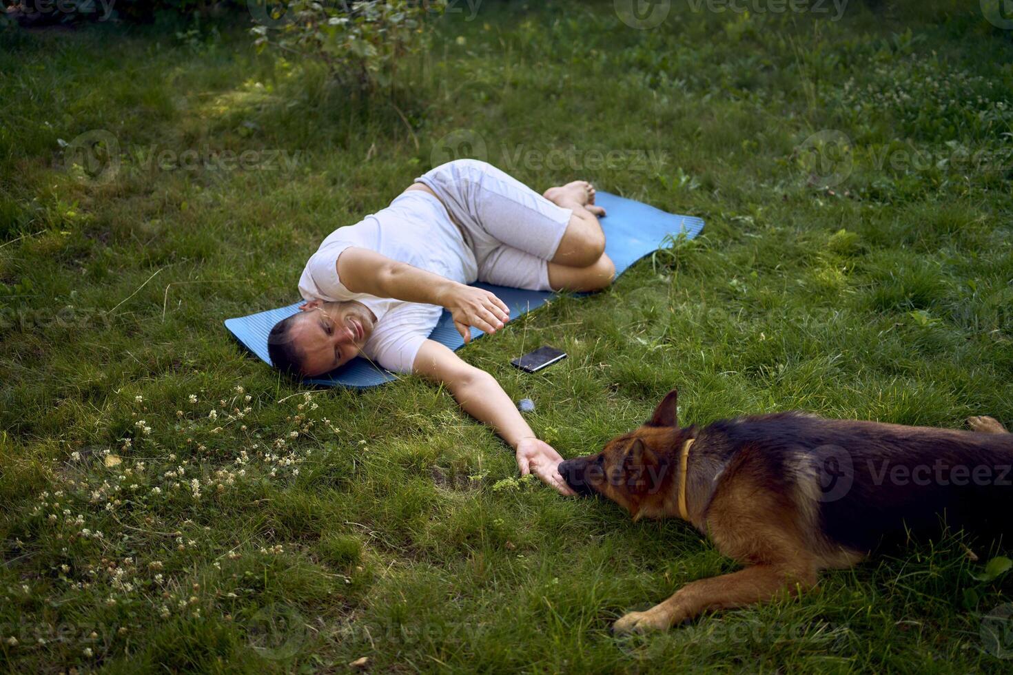 man does somatic exercises with his dog in the garden in the morning photo