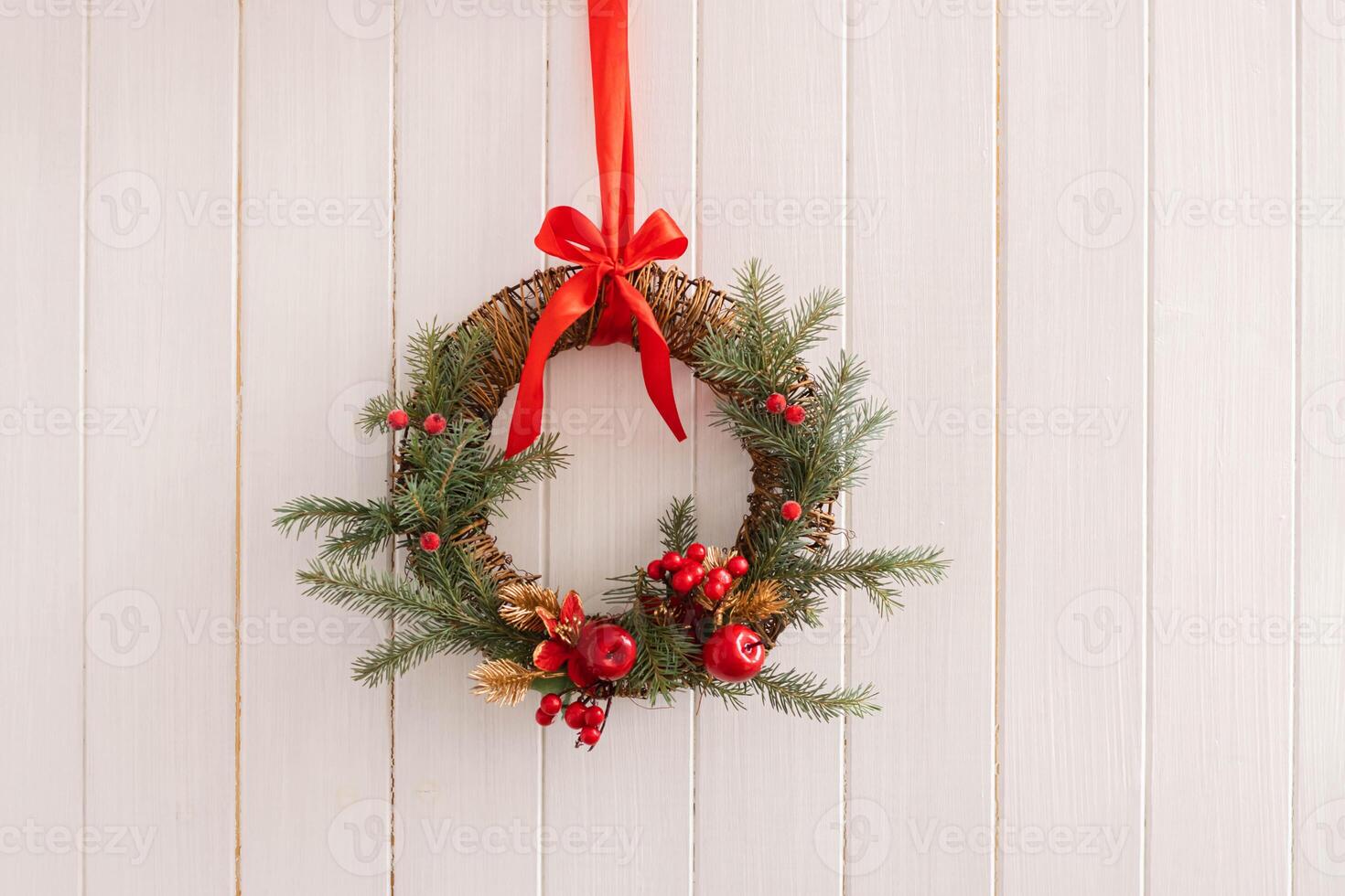 Traditional Christmas wreath of fir branches with red berries bright ribbons white wooden background photo