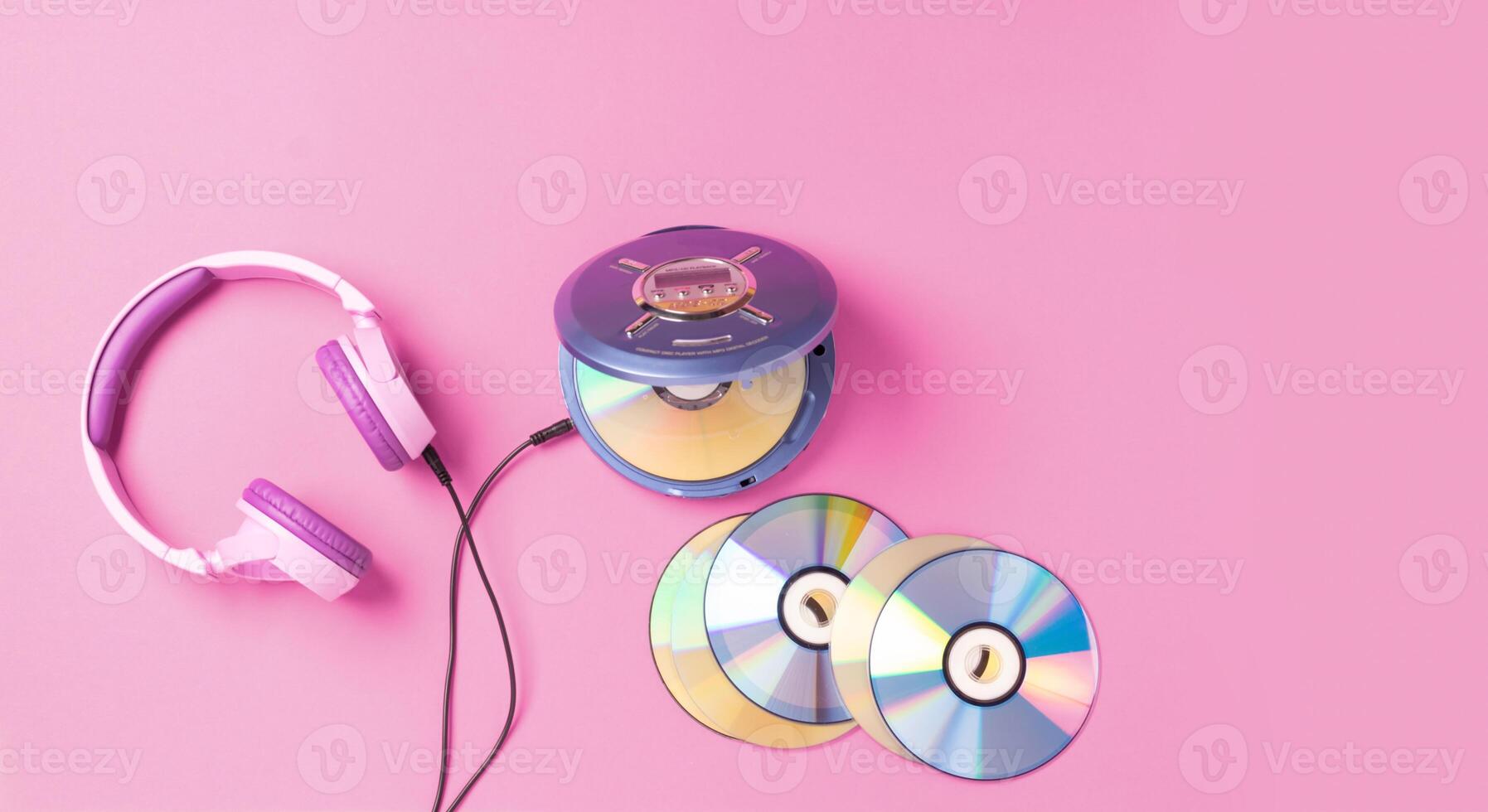 Personal compact portable CD player disks purple headphones on a pink background. photo