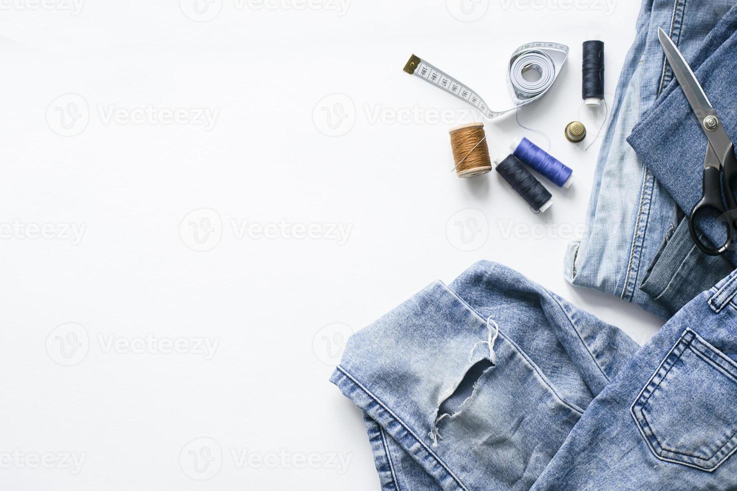 Handicraft, clothing repair. Ripped blue jeans sewing accessories white background. The concept of economical things. photo