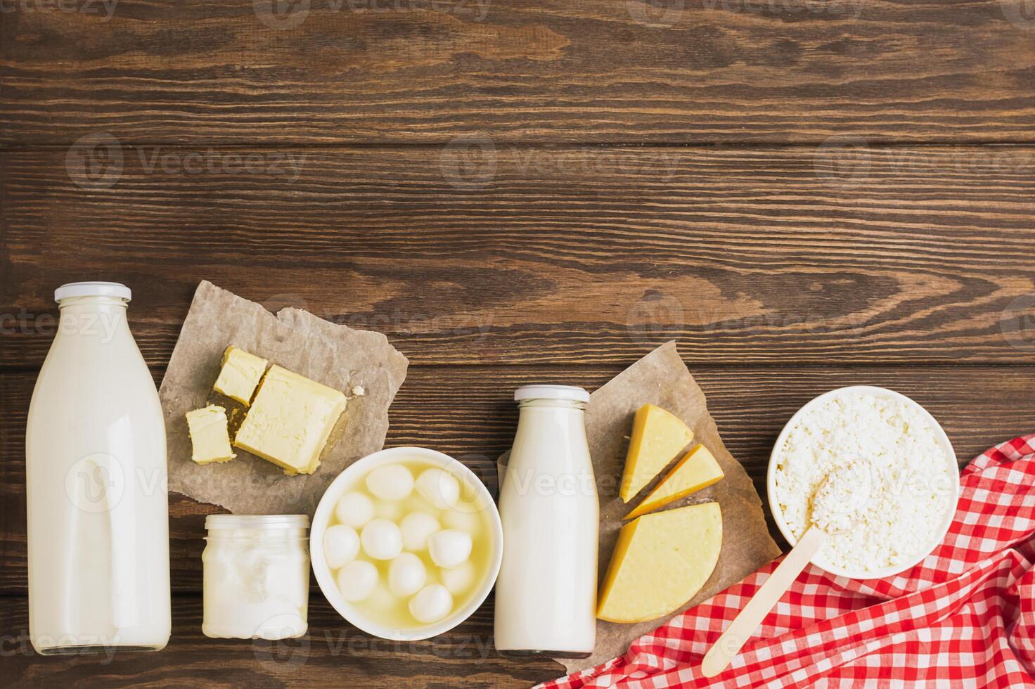 Dairy sour milk products on a wooden dark rustic background. Milk, kefir, yogurt, butter, cheese assortment. Flat layout photo