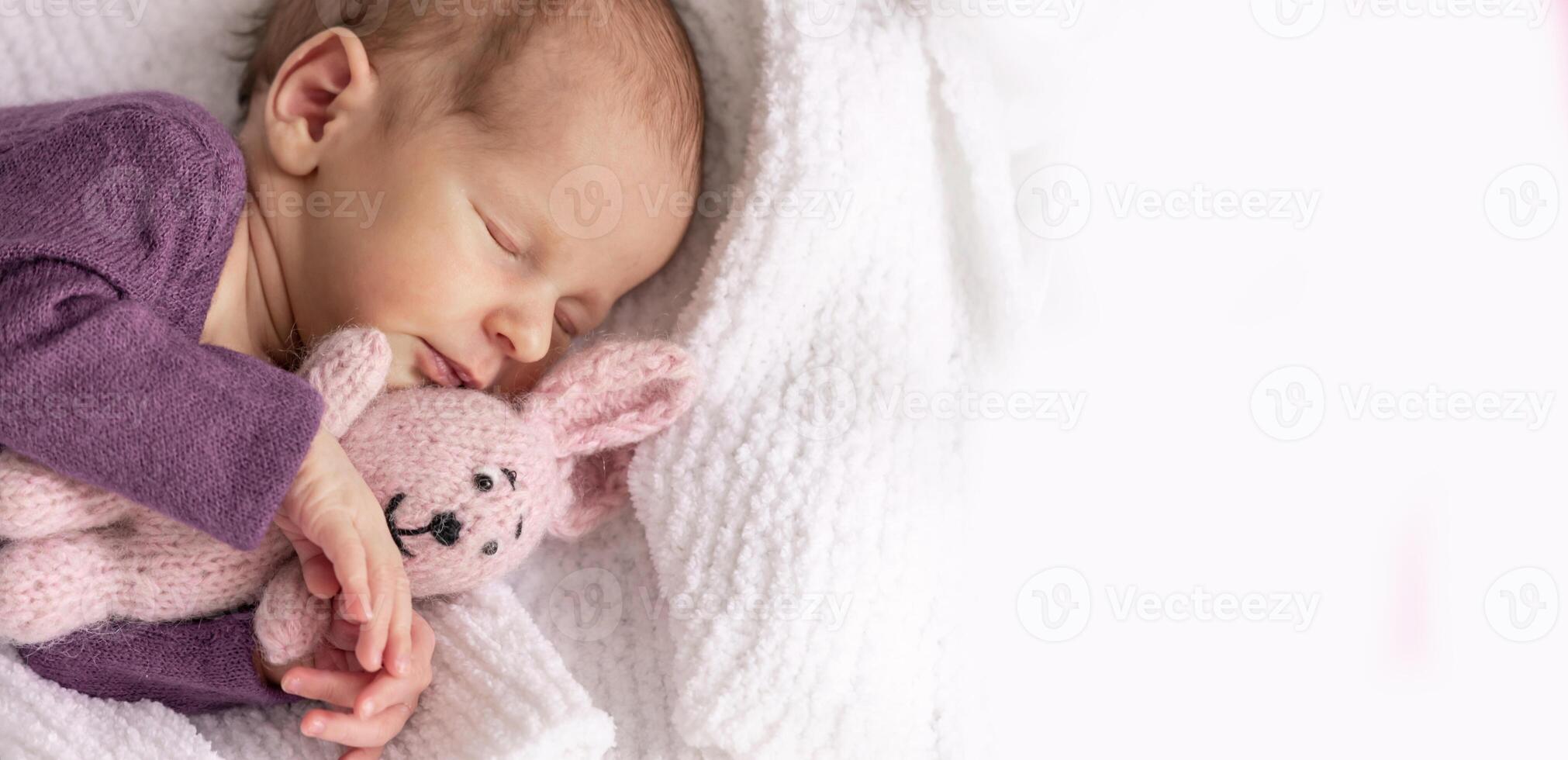 Cute newborn baby girl sleeps with her favorite toy, the first month of life. Close-up soft focus photo