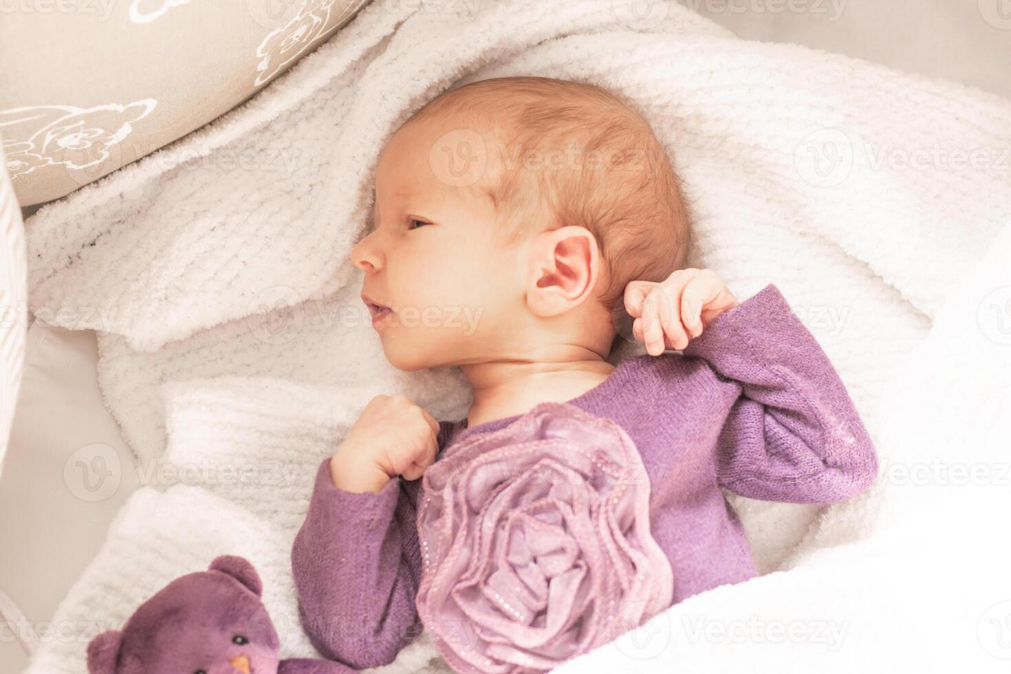 Cute newborn baby girl sleeps at home in her crib with her favorite toy, the first month of life photo