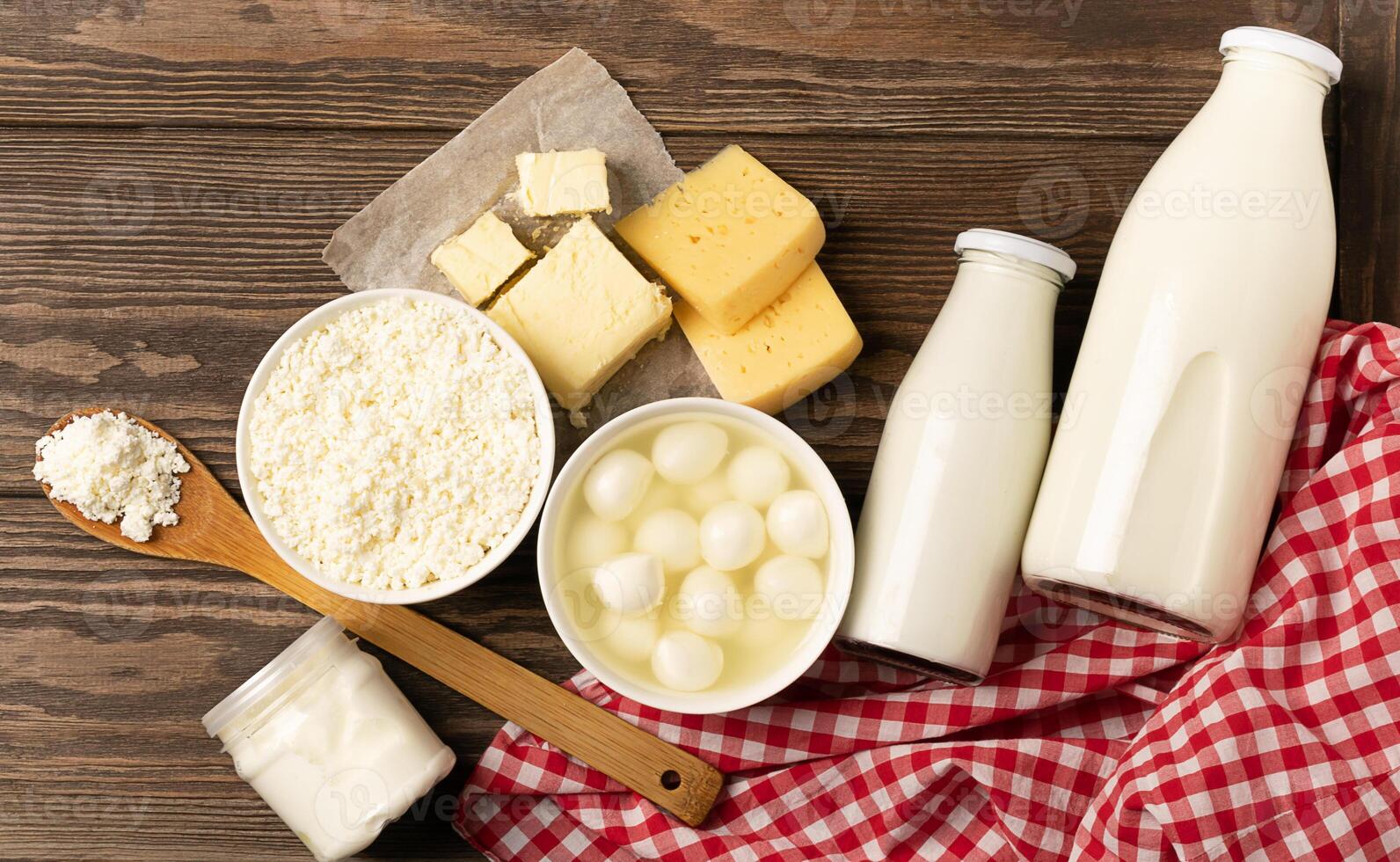 Dairy sour milk products on a wooden dark rustic background. Milk, kefir, yogurt, butter, cheese assortment. Flat layout photo