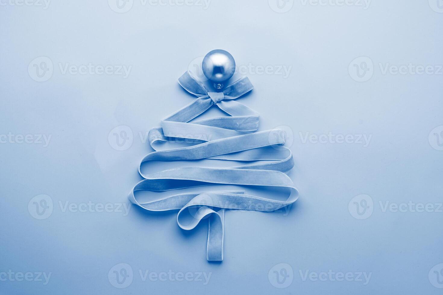 Christmas creative tree made of ribbon decorated with golden ball a pastel pink background. Festive minimalism concept. photo