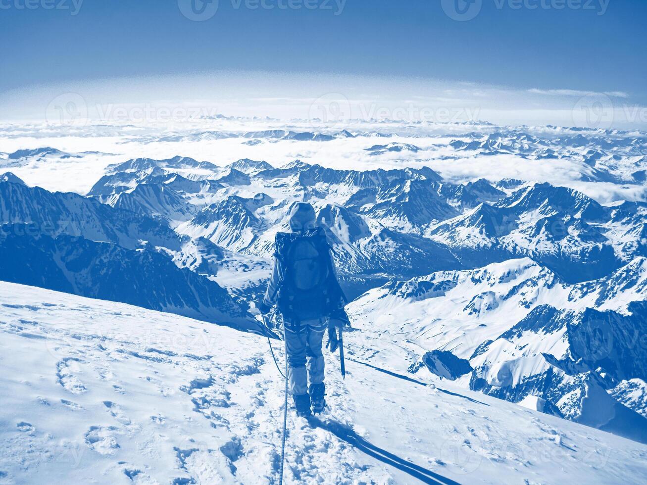 Man climber on top of a beautiful snow-capped mountain. The concept of extreme recreation and adventure. photo