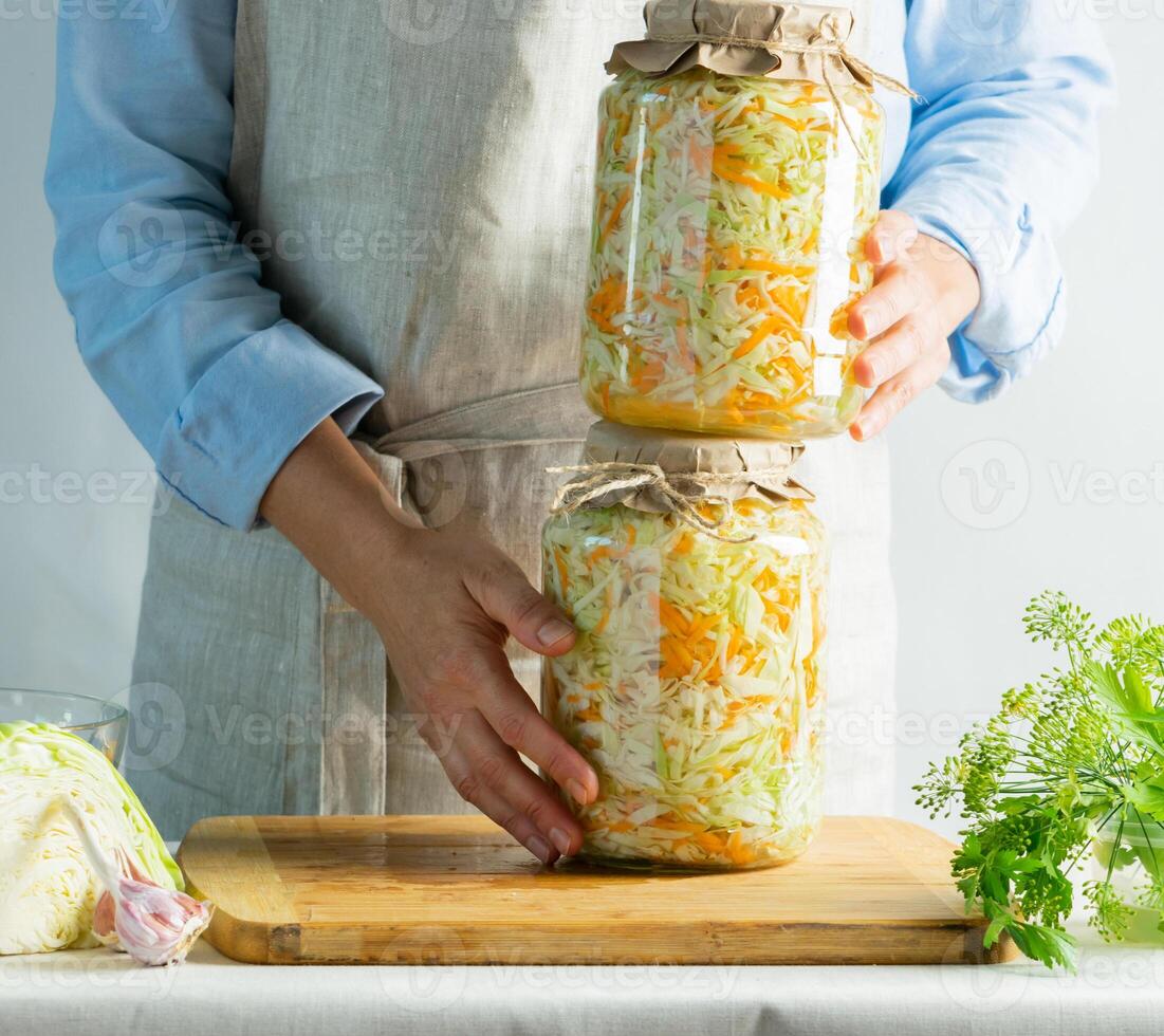 Fermentation preservation Sauerkraut in glass jars in the hands of a woman natural background. Canned food concept. photo