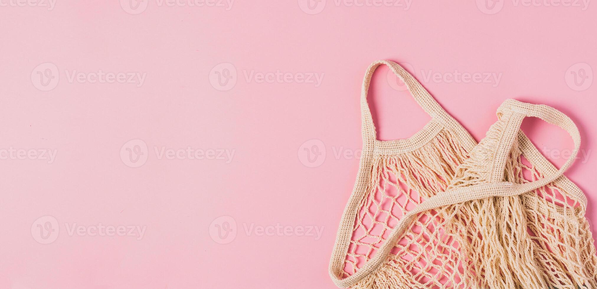 Fashionable braided string bag empty on pink pastel background. Horizontal frame copy space banner photo