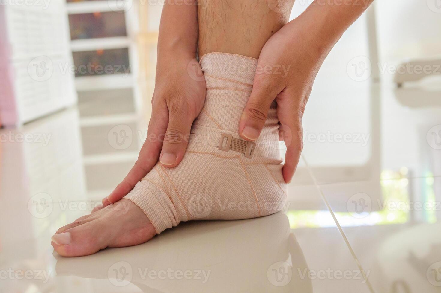 Man with ankle sprain elastic bandage for ankle injury and feeling pain photo