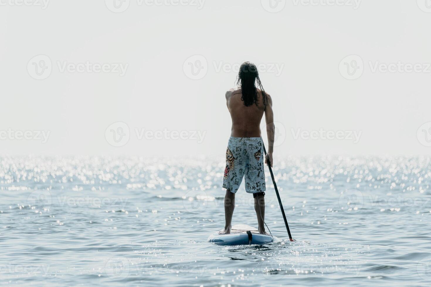 Man Sup Sea. Strong athletic man learns to paddle sup standing on board in open sea ocean on sunny day. Summer holiday vacation and travel concept. Aerial view. Slow motion photo