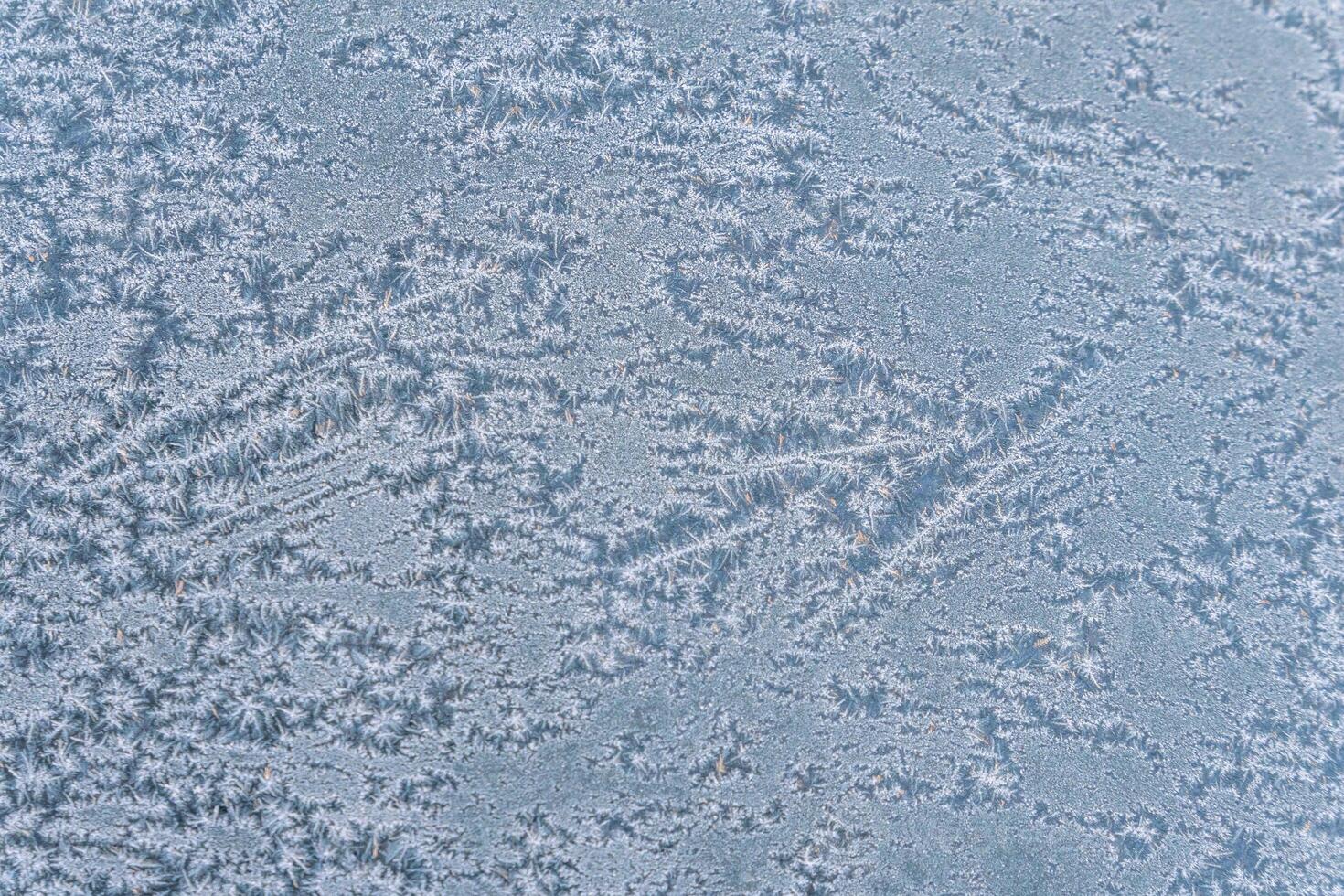 Selective focus. First frost on a frozen car, late autumn close-up. Beautiful abstract frozen microcosmos pattern. Freezing weather frost action in nature. Winter backdrop. photo