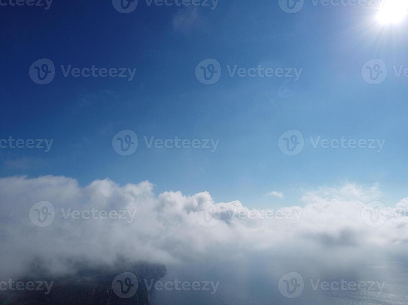 Aerial view. The drone flies over foggy and fluffy clouds. Blue sky sun and sea fog. Abstract aerial nature summer ocean sunset sea and sky background. Vacation, travel and holiday concept photo