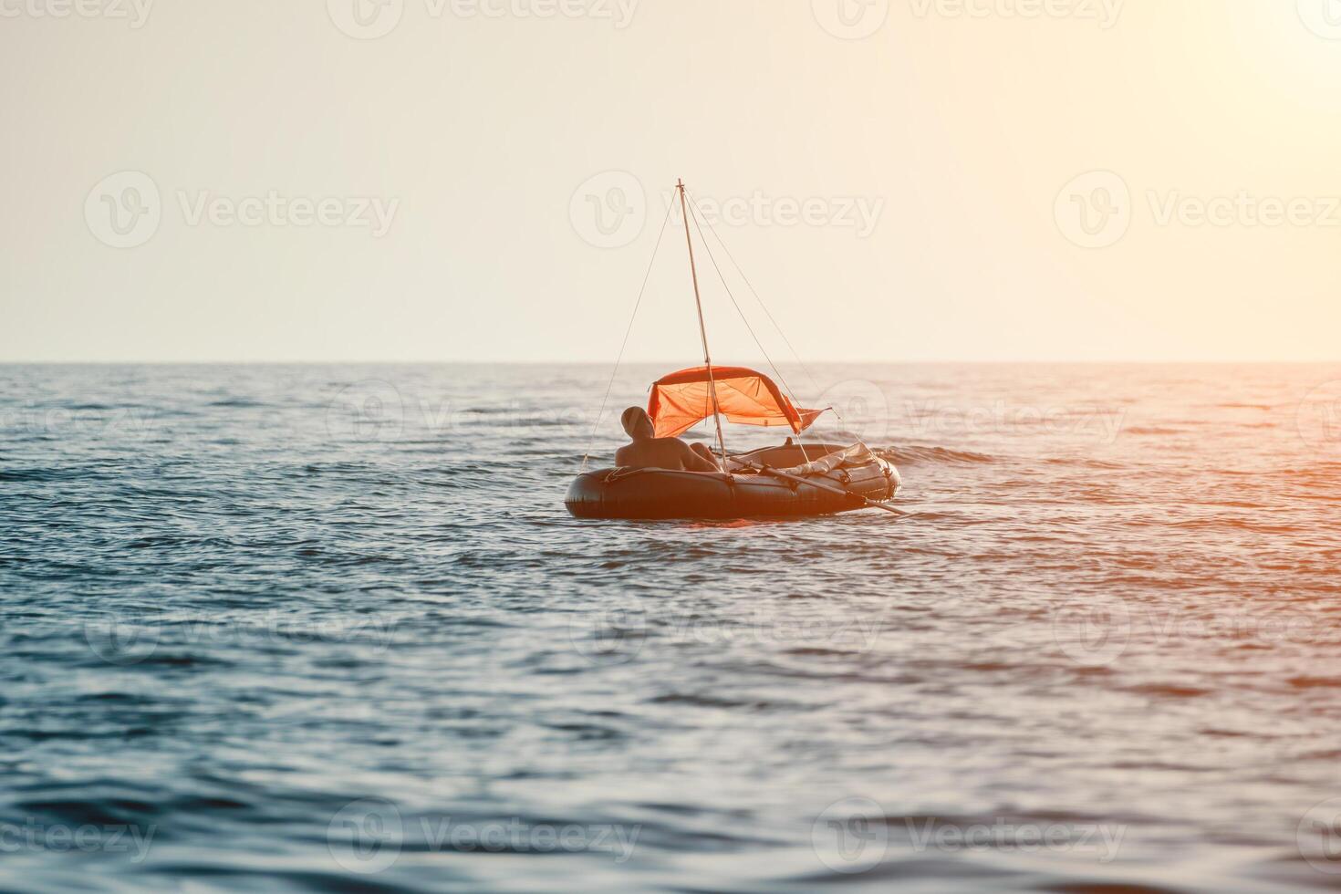 Fisher sea boat. Tourist maneuvering an inflatable boat while fishing in a life jacket, with the beautiful sunset sea in the background. a relaxing fishing trip. photo