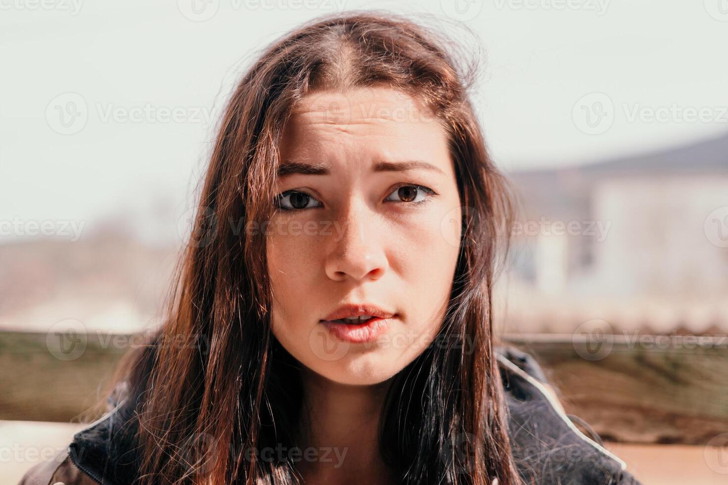 Happy young smiling woman with freckles outdoors portrait. Soft sunny colors. Outdoor close-up portrait of a young brunette woman and looking to the camera, posing against autumn nature background photo