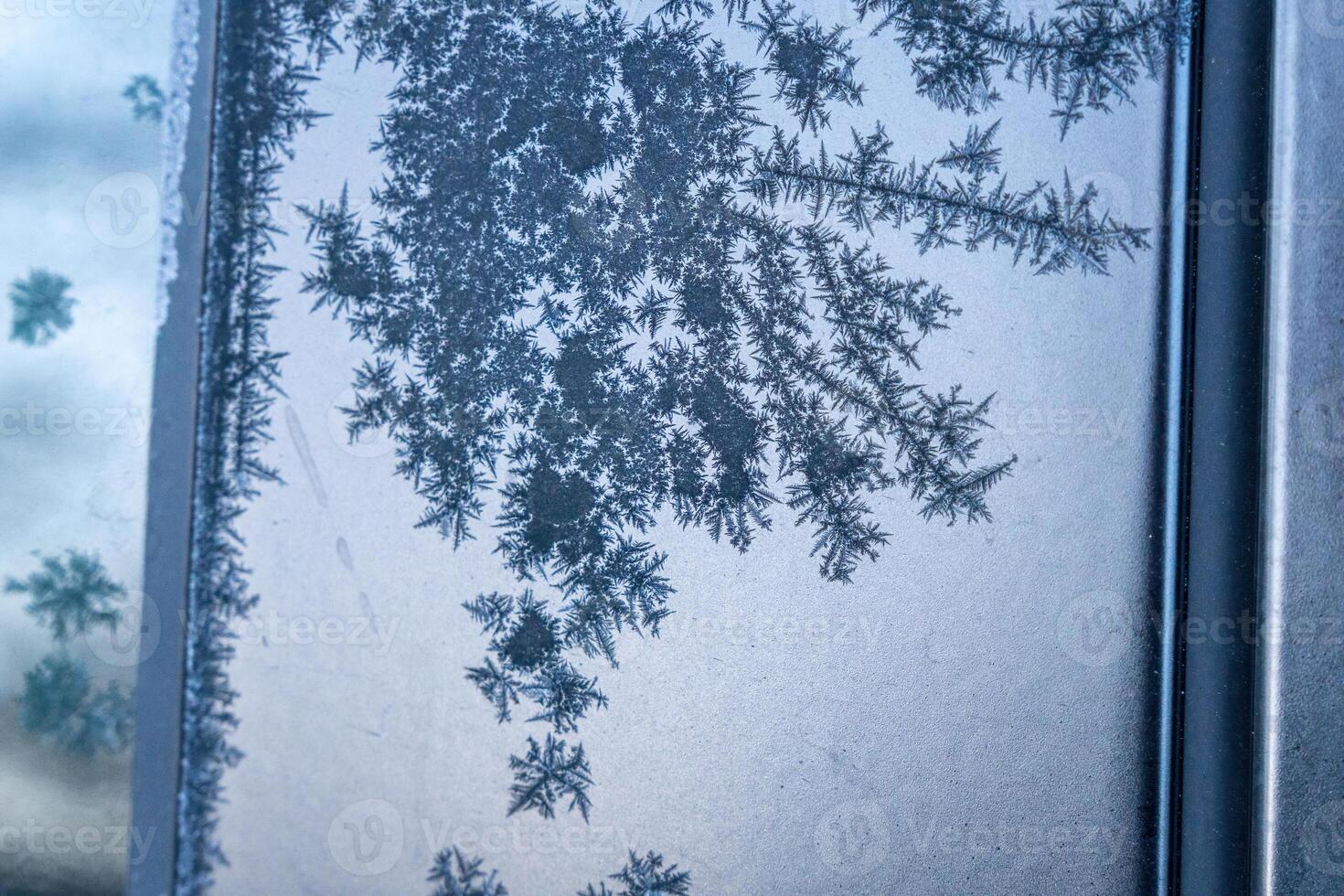 Selective focus. First frost on a frozen black plastic, late autumn close-up. Beautiful abstract frozen microcosmos pattern. Freezing weather frost action in nature. Winter backdrop. photo