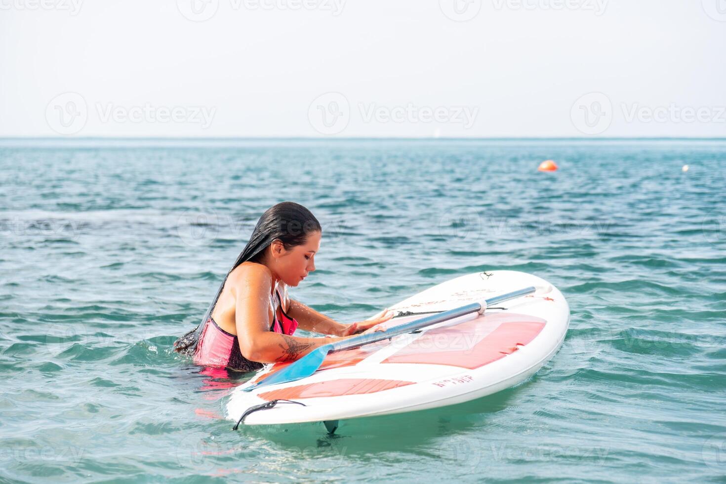 Sea woman sup. Silhouette of happy young woman in pink bikini, surfing on SUP board, confident paddling through water surface. Idyllic sunset. Active lifestyle at sea or river photo