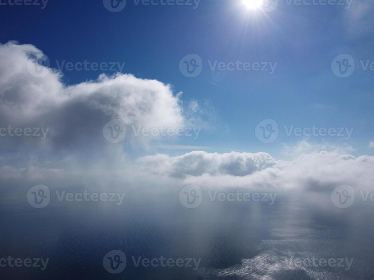 Aerial view. The drone flies over foggy and fluffy clouds. Blue sky sun and sea fog. Abstract aerial nature summer ocean sunset sea and sky background. Vacation, travel and holiday concept photo