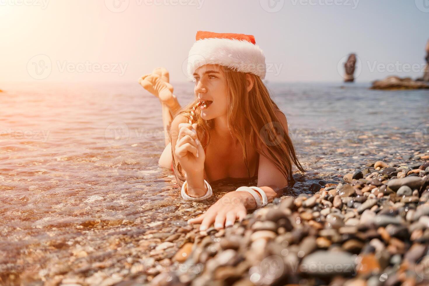 Woman travel sea. Happy tourist enjoy taking picture on the beach for memories. Woman traveler in Santa hat looks at camera on the sea bay, sharing travel adventure journey photo