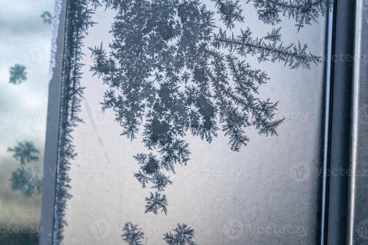 Selective focus. First frost on a frozen black plastic, late autumn close-up. Beautiful abstract frozen microcosmos pattern. Freezing weather frost action in nature. Winter backdrop. photo