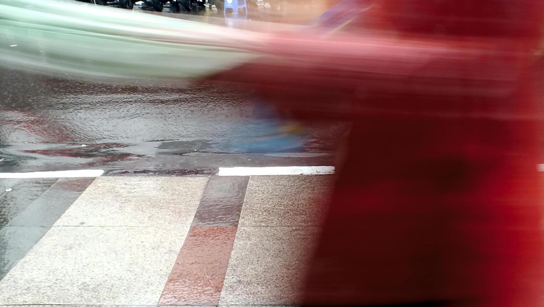 Blurred motion of unknown person pedestrians walking on wet city pavement during a rainy days photo