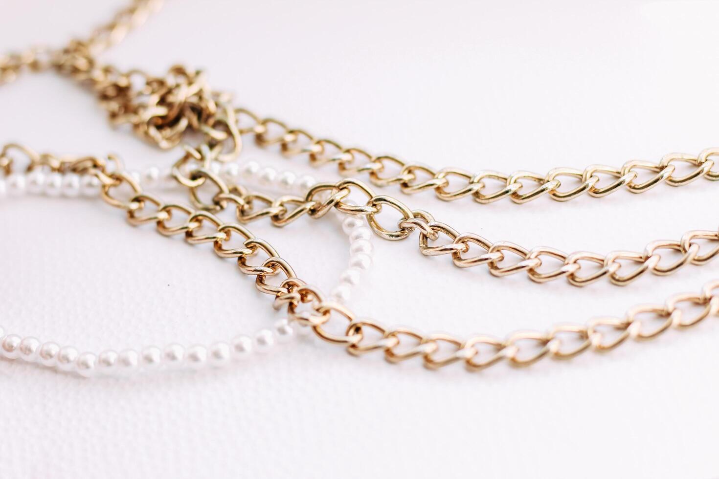 A necklace of white beads with chains of jewelry on a white aesthetic background. photo