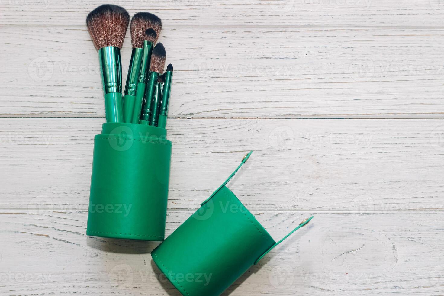 Green case with make-up bones on a wooden table. photo