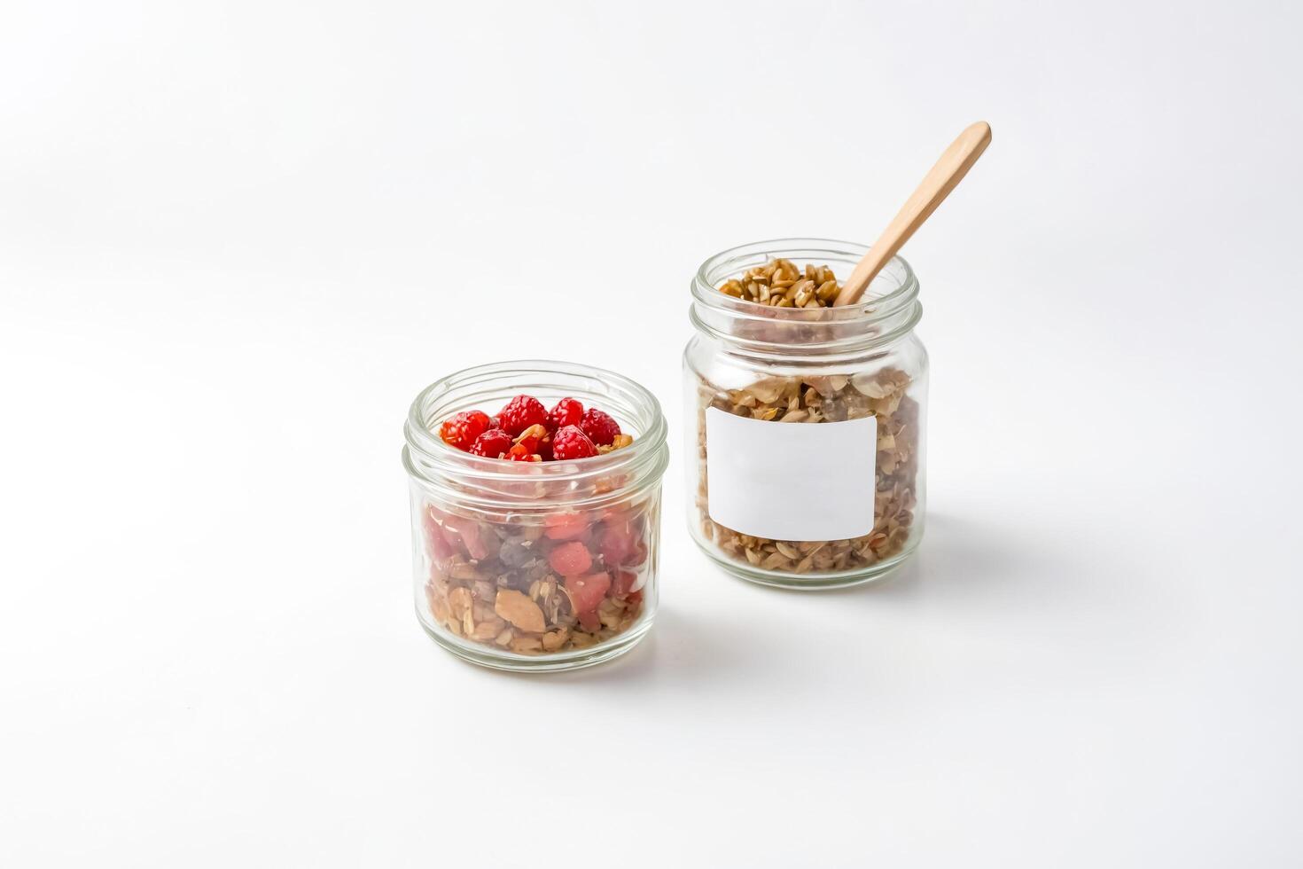 Two Jars of Granola with Raspberries on a White Background photo