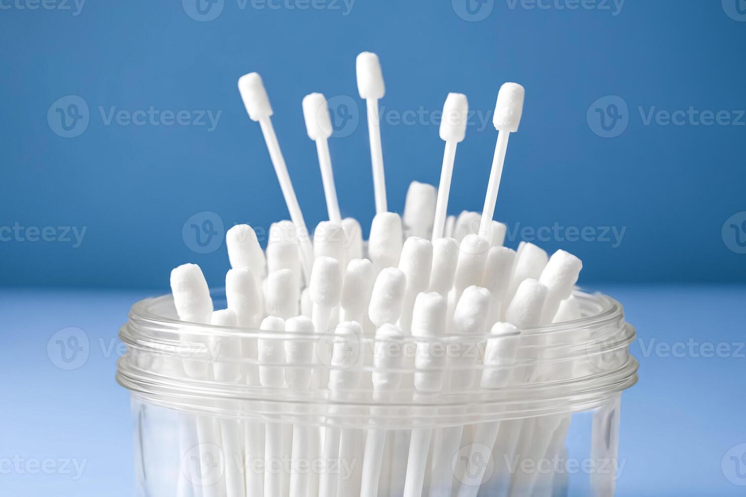 Close-up of Cotton Swabs in Glass Jar on Blue Background photo