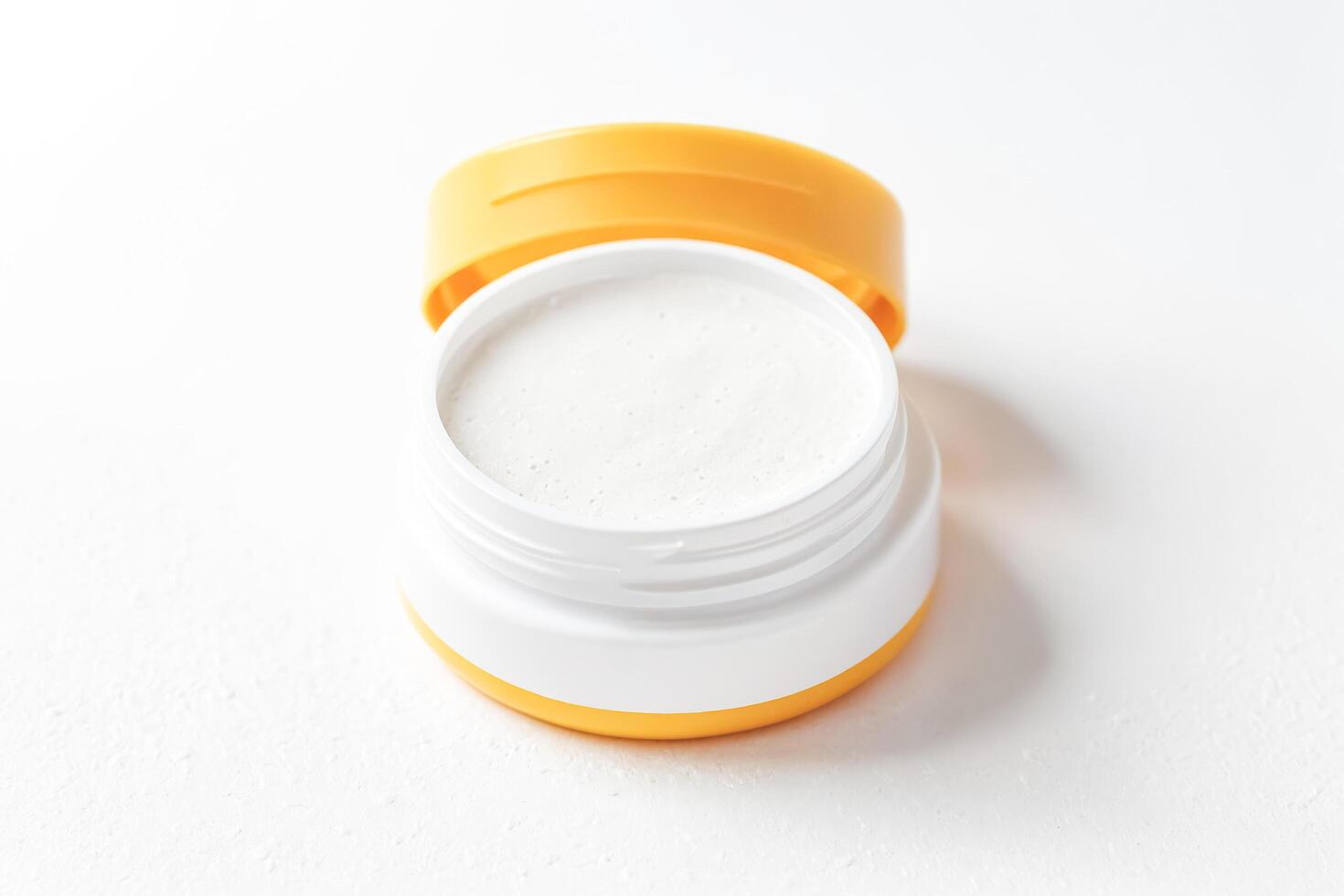 Open Jar of White Cream with Yellow Lid photo