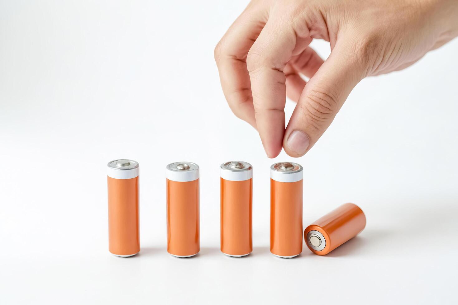 Hand Picking Up a Battery from a Row of Batteries photo