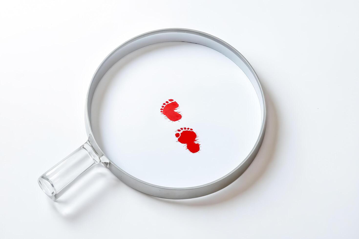 Magnifying Glass Over Red Footprints photo
