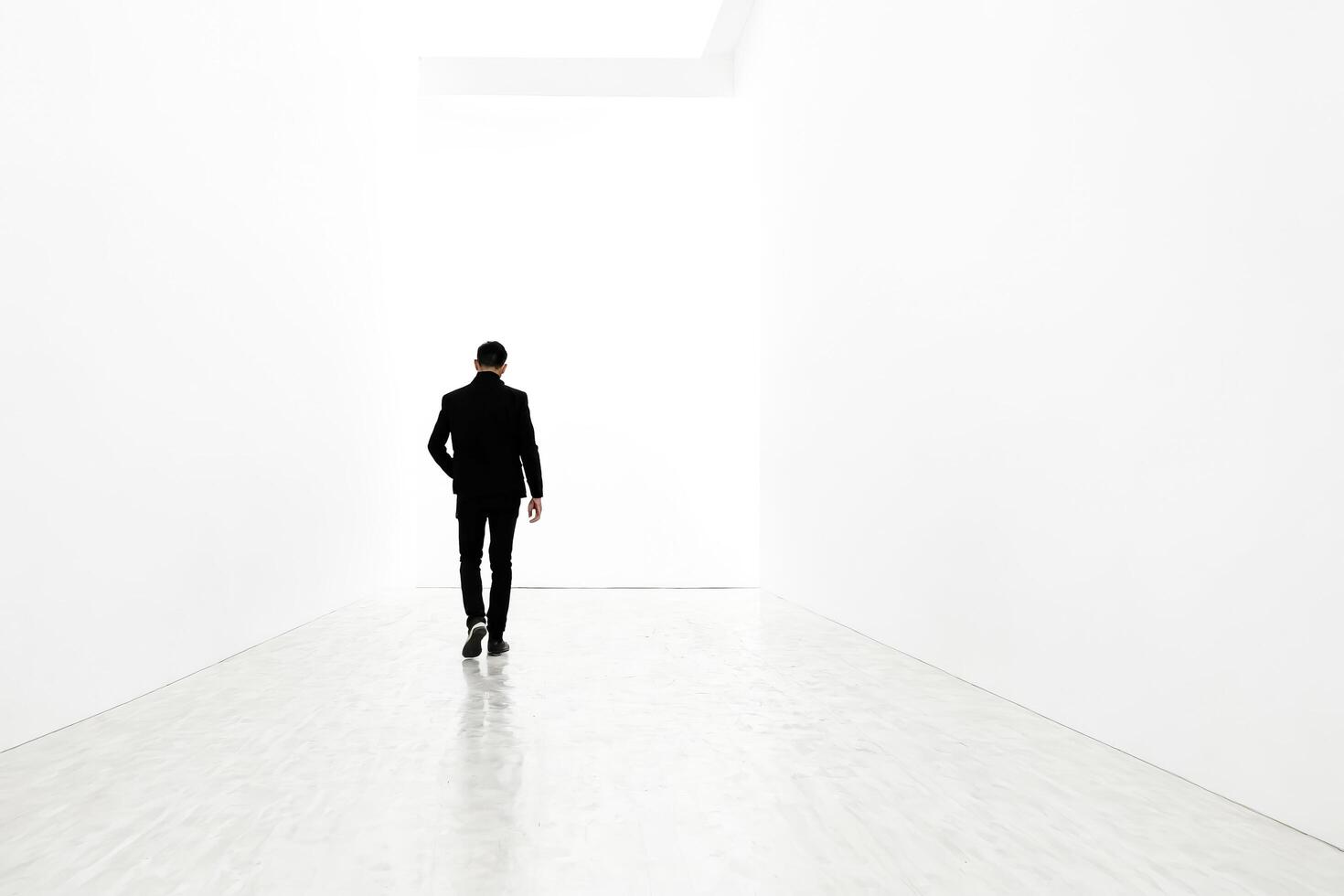 Man walking towards the light in a white room photo