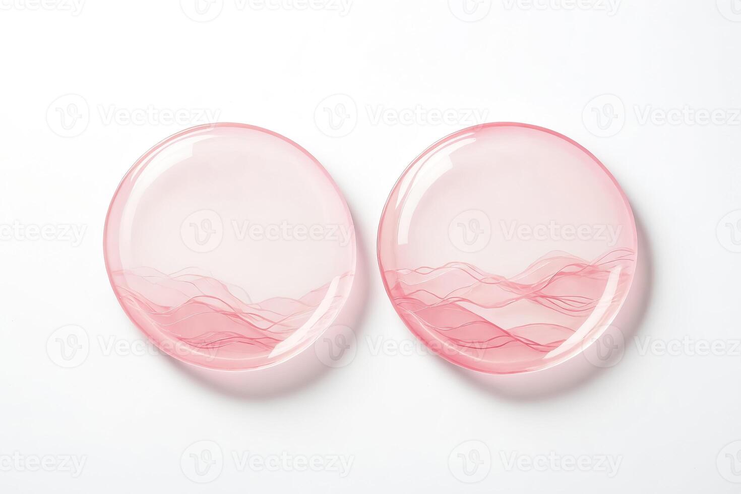 Two pink glass plates with wavy design on white background photo
