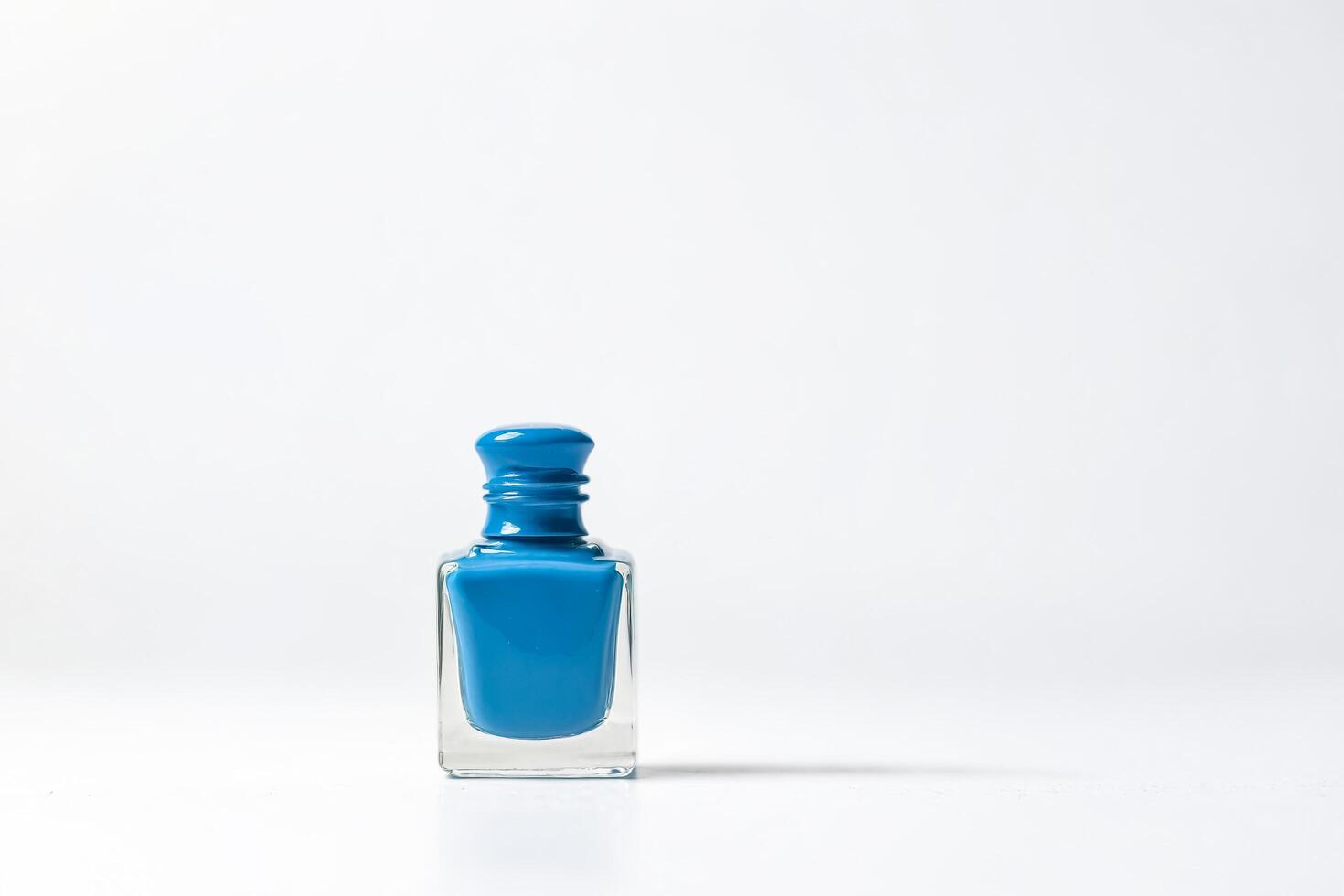 Blue nail polish bottle on white background photo