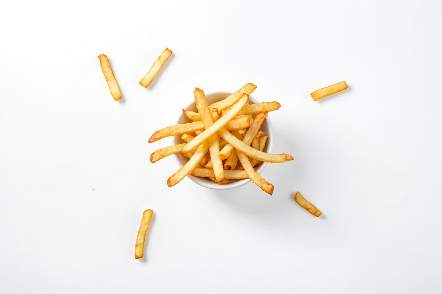 French Fries in a Bowl with Scattered Fries on a White Background photo