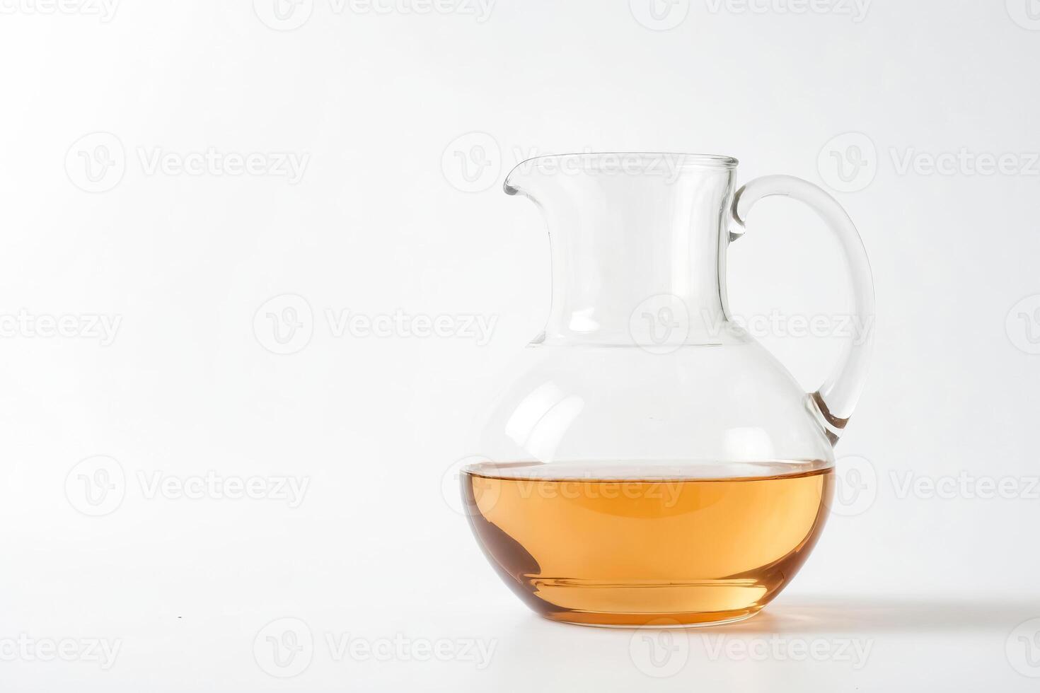 Glass pitcher with golden liquid on white background photo