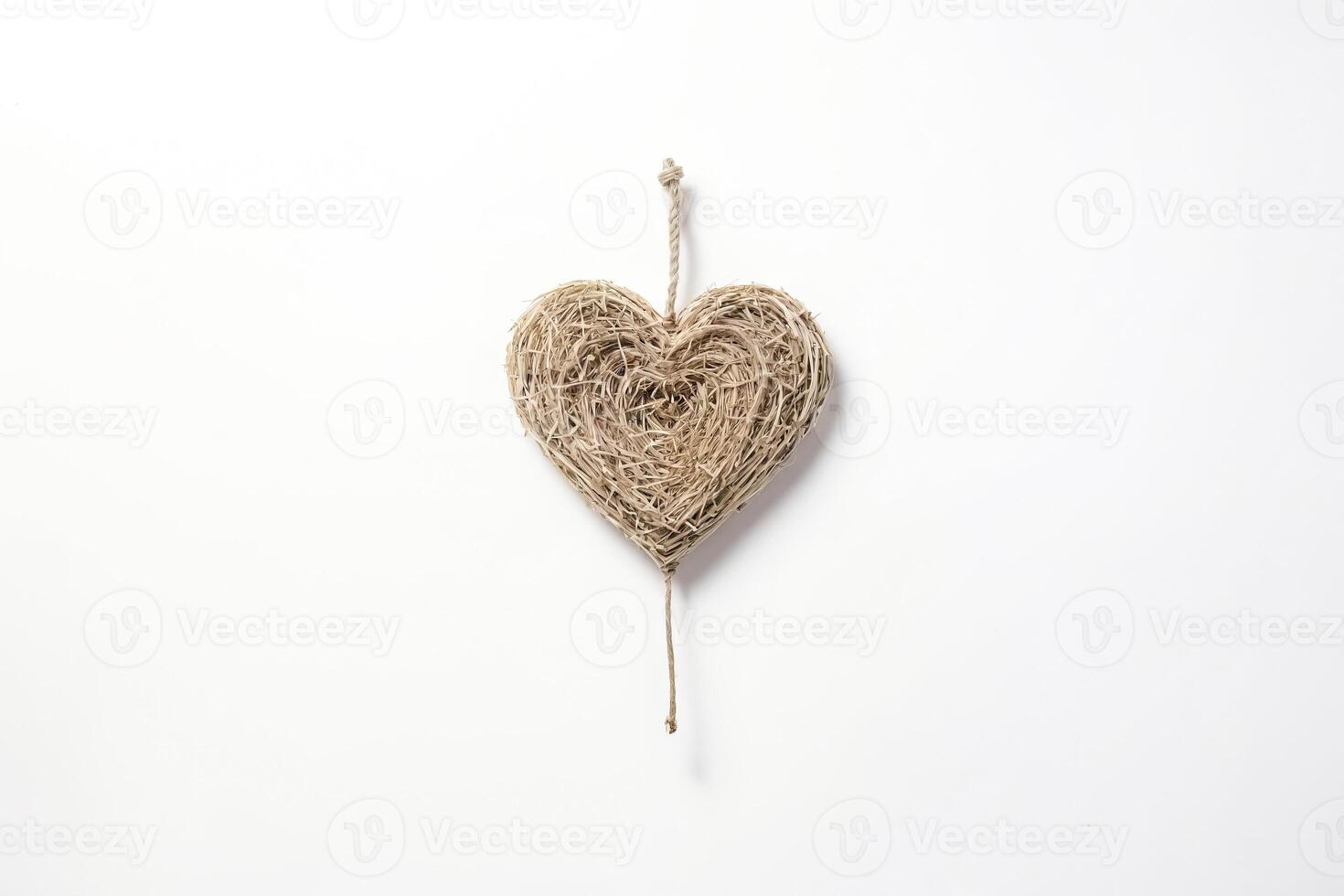 Hanging straw heart on white background photo