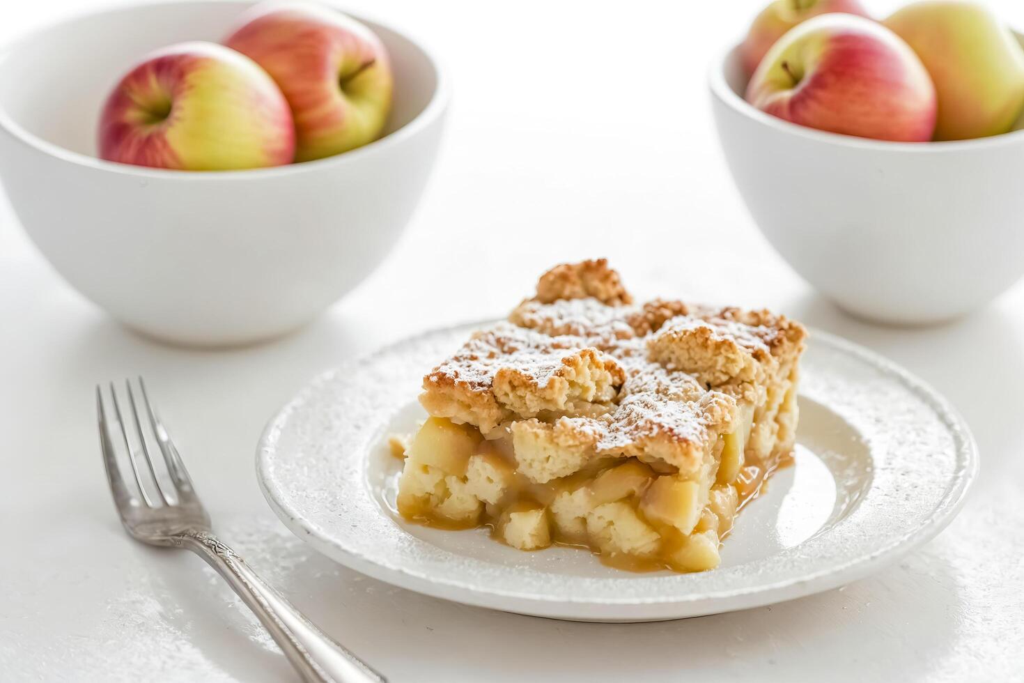 Closeup of a slice of apple crumble with powdered sugar on a white plate photo