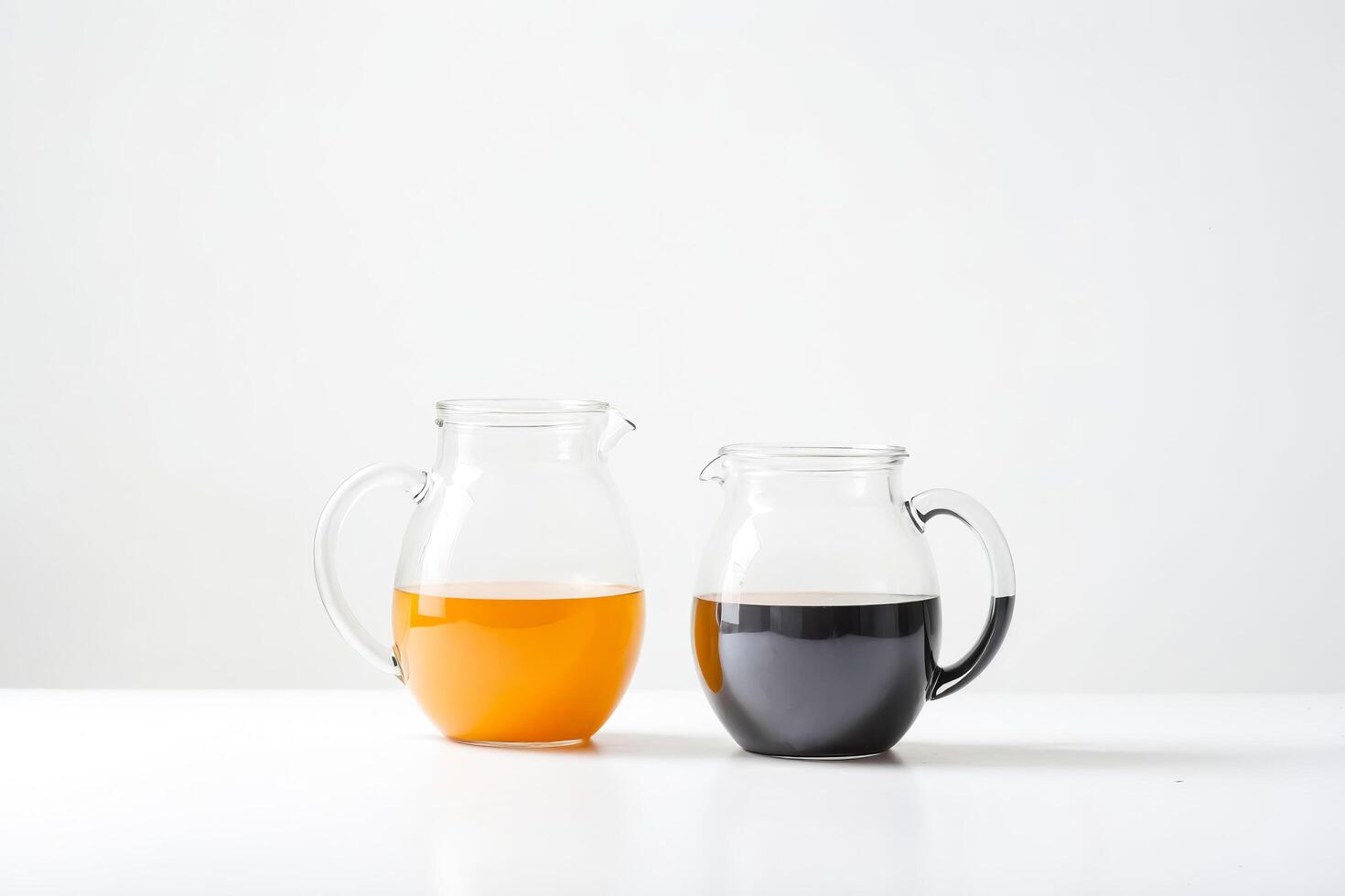 Two Glass Pitchers with Orange and Black Liquid photo