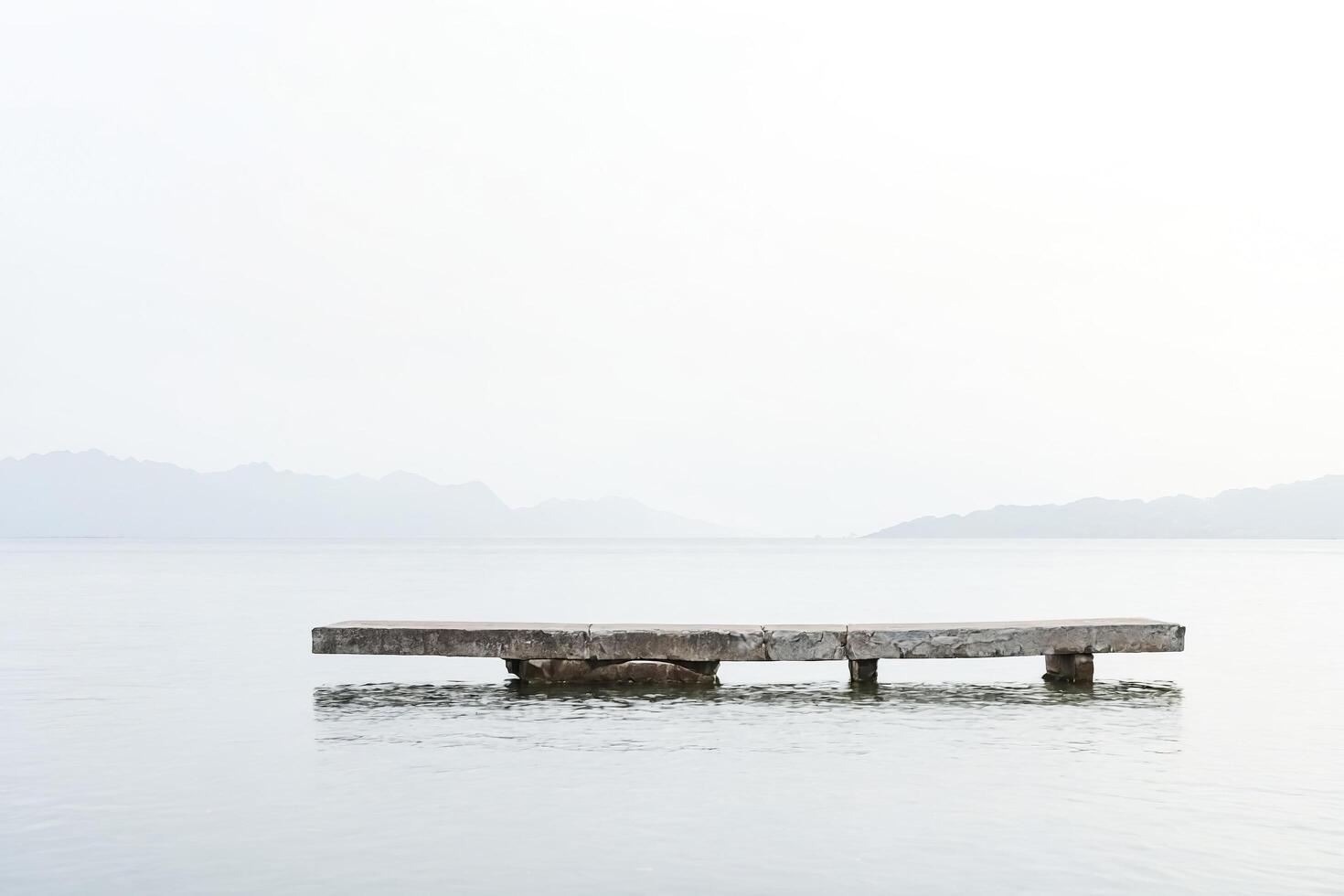 Minimalist Concrete Dock on Calm Water with Mountains in the Background photo