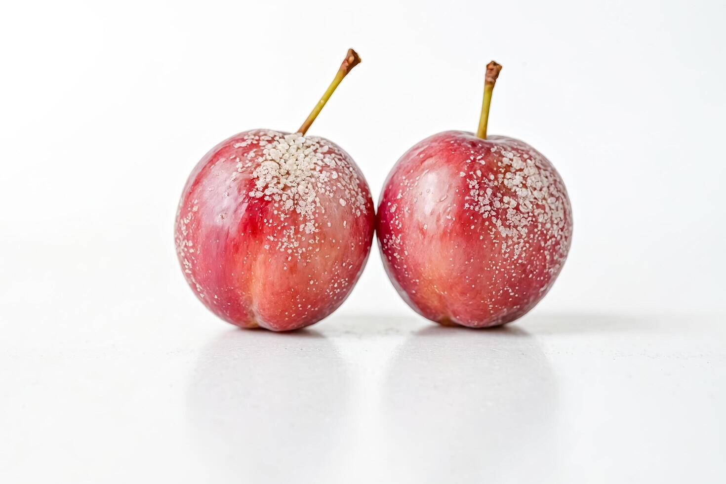 Two Red Plums with White Frosting on a White Background photo