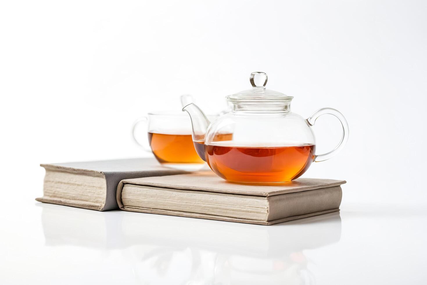 Glass Teapot and Cup on Stack of Books photo