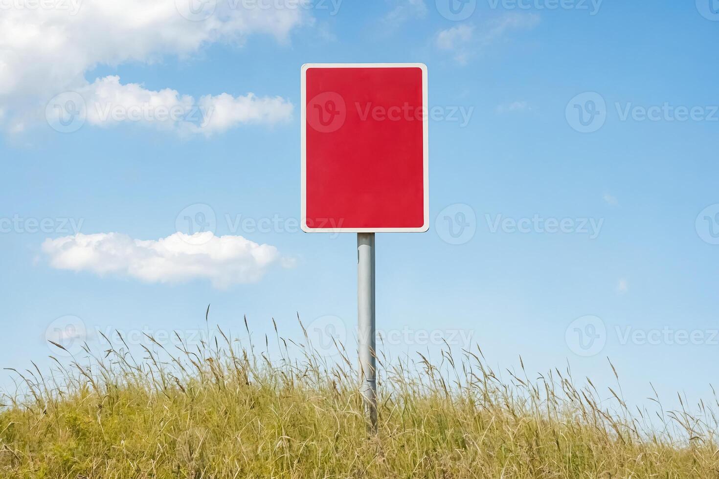 Red Blank Sign in Grass Field Against Blue Sky photo