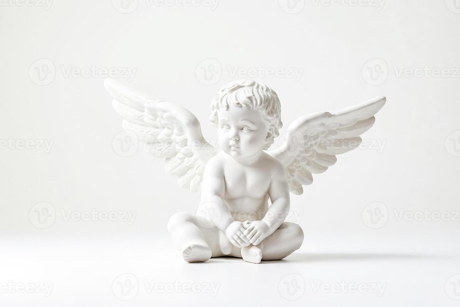 White Angel Figurine Sitting on White Background photo