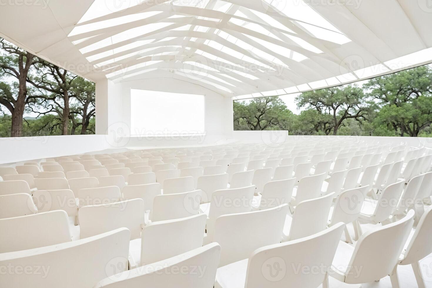 Empty white chairs facing a blank screen in a modern amphitheater photo